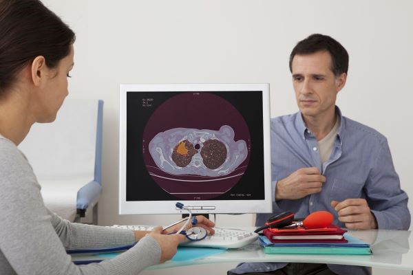 lung image on a pc with a middle aged man in the background