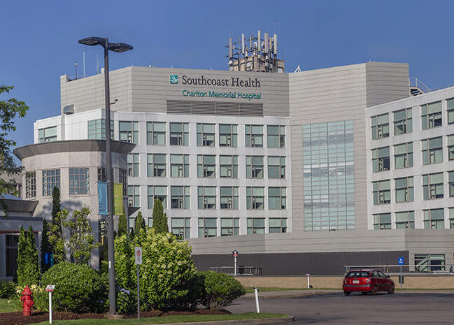 Charlton Memorial Hospital, a large modern medical facility with an American flag and green landscaping.
